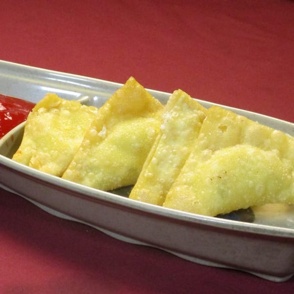 Crispy golden fried wontons with a side of red dipping sauce in a gray dish.